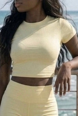 Woman in a yellow ÁMBER Del Mar summer set standing on a wooden pier by the ocean.