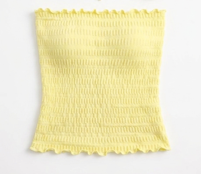 Model wearing an ÁMBER Del Mar lettuce trim yellow smocked tube top on a sunny beach, ideal for a coastal-chic summer outfit