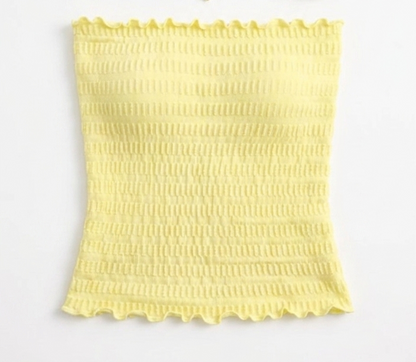 Model wearing an ÁMBER Del Mar lettuce trim yellow smocked tube top on a sunny beach, ideal for a coastal-chic summer outfit