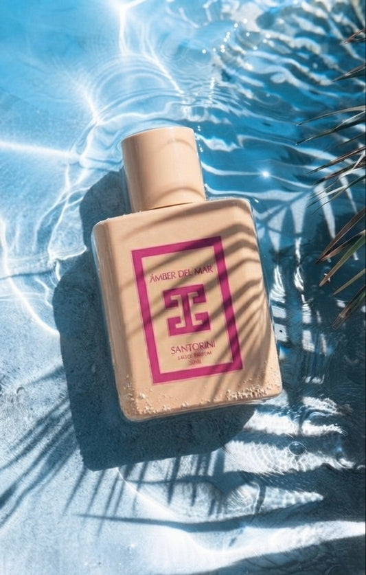 Santorini Eau de Parfum by ÁMBER DEL MAR summer fragrance bottle resting in crystal clear pool water with tropical palm leaf shadows.