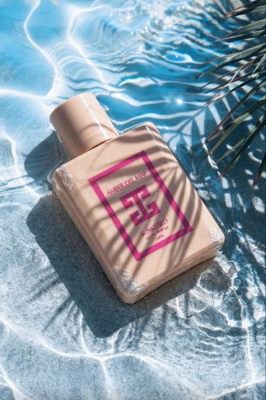Sunkissed Eau de Parfum by ÁMBER DEL MAR summer fragrance bottle resting in crystal clear pool water with tropical palm leaf shadows.